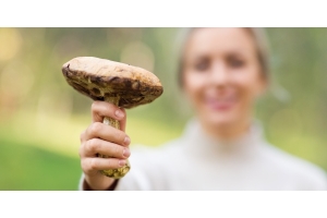 Frau zeigt einen Pilz als Quelle für Proteine bei veganer Ernährung