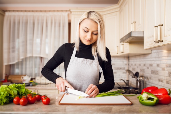 Frau bereitet Essen bei Stimmungsschwankungen vor der Periode zu