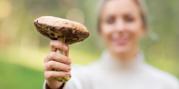 Frau zeigt einen Pilz als Quelle für Proteine bei veganer Ernährung