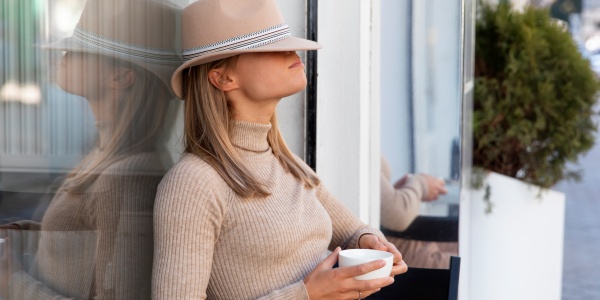 Frau trinkt in der frischen Luft eine Tasse Tee, um Erkältungen vorzubeugen